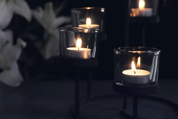 Burning candles on dark background. Funeral symbol