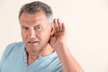Mature man with hearing problem on white background clipart