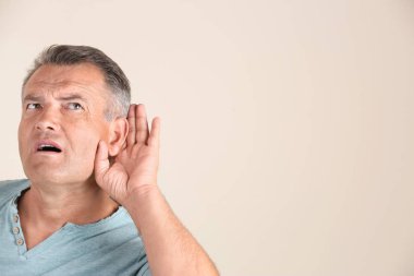Beyaz arka planda işitme sorunu olan olgun bir adam