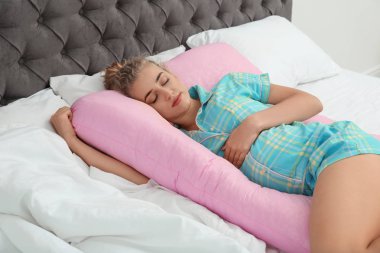 Evde yatakta hamile yastığı ile uyuyan güzel hamile kadın