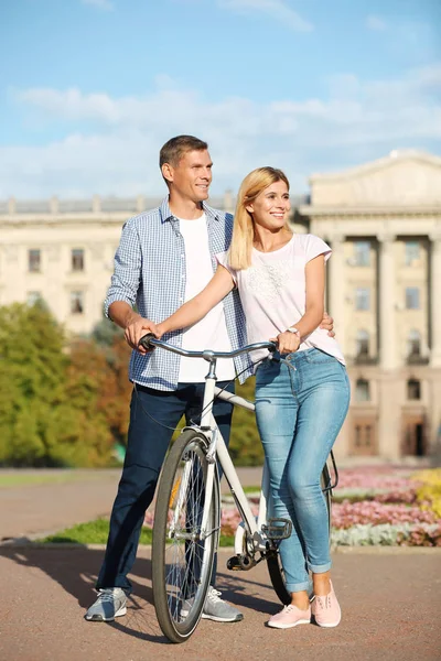 Happy couple with bicycle outdoors on sunny day