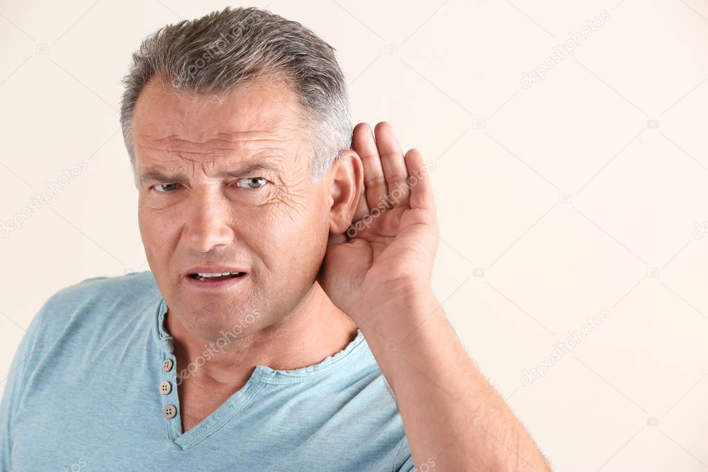 Mature man with hearing problem on white background