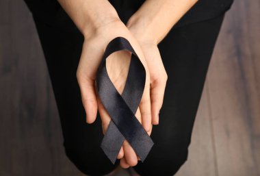 Woman holding black ribbon, closeup. Funeral symbol clipart