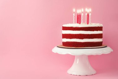 Pembe bir arka plan üzerinde mum ile lezzetli ev yapımı kırmızı kadife kek. Metin için yer