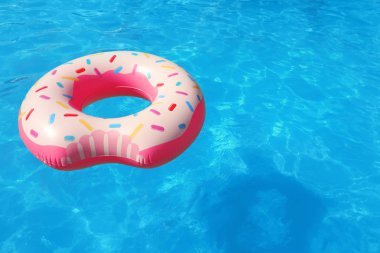 Güneşli günde yüzme havuzunda yüzen şişme yüzüğü. Metin için yer