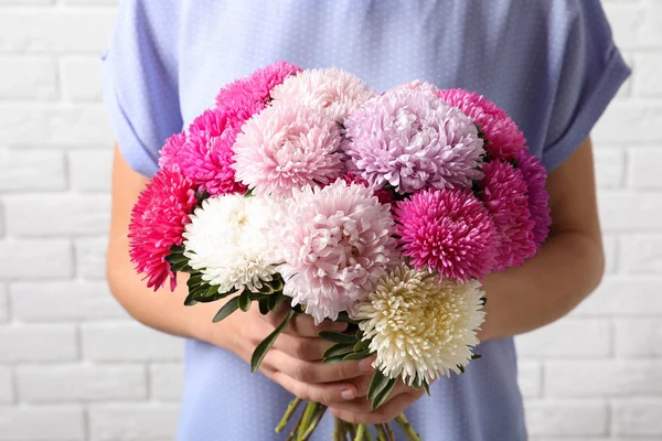 Kvinna Med Vackra Aster Blombukett Mot Tegelvägg — Stockfoto