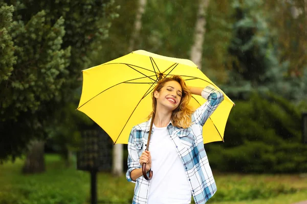 公園で雨の下で傘を持つ幸せな若い女性 — ストック写真