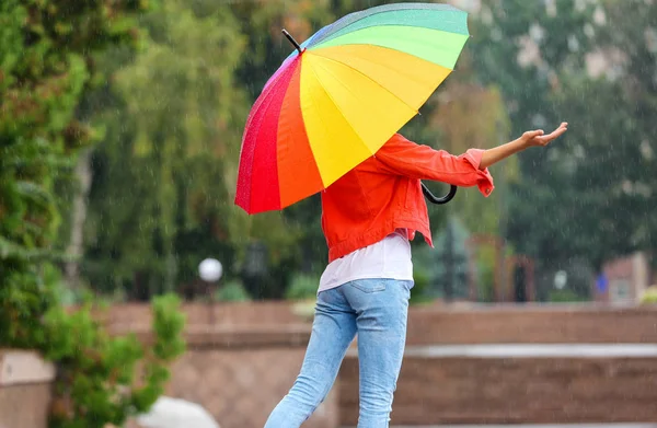 屋外の雨の下で明るい傘を持つ若い女性 — ストック写真