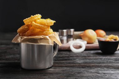 Dishware ahşap masa üzerinde ev yapımı çıtır çıtır kızarmış soğan halkası ile. Metin için yer