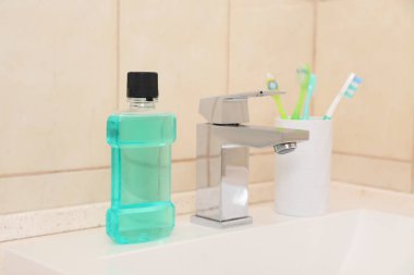Diş macunu ve diş fırçası ile sahibi içinde banyo lavabo. Diş ve ağız bakımı