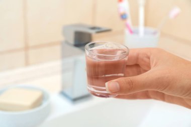 Cam ile gargara diş ve ağız bakımı için banyoda tutan kadın