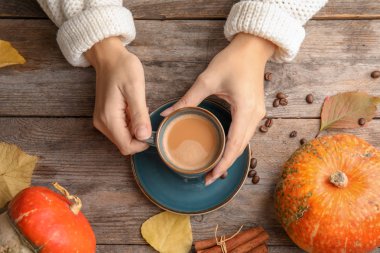 Bardak kabak spice latte ahşap arka plan, üstten görünüm üzerinde tutan kadın