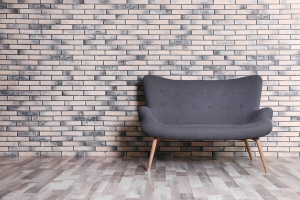 Room interior with comfortable sofa near brick wall. Space for text