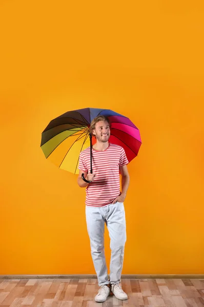 Человек Радужным Зонтиком Возле Цветной Стены — стоковое фото