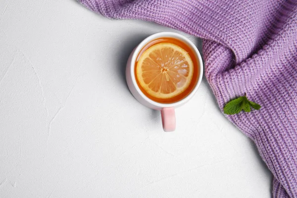 Cup with hot tea and lemon on light background, top view. Space for text