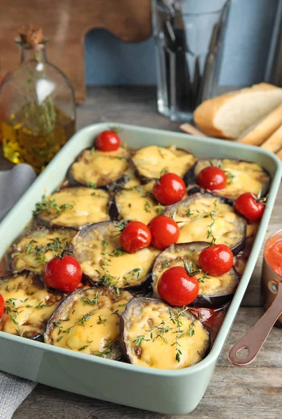 焼き茄子のトマトとチーズの木製テーブルの上の食器 — ストック写真