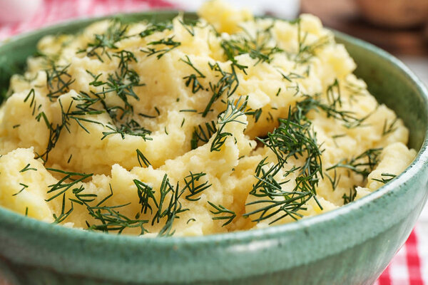 Tasty mashed potatoes served with dill in bowl, closeup
