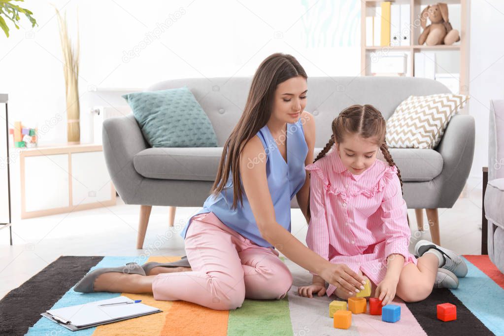 Child psychologist and little girl playing with cubes in office