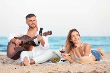 Kumsalda romantik akşam yemeği gitar ile genç çift