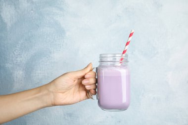 Lezzetli milkshake renk arka plan, closeup üzerinde mason kavanoz kadınla