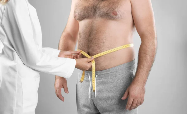 Arzt Misst Die Taille Des Mannes Auf Grauem Hintergrund Nahaufnahme — Stockfoto