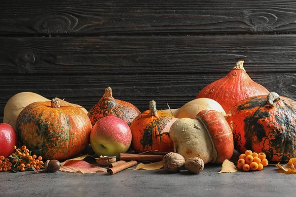 Samenstelling Met Verschillende Pumpkins Tafel Tegen Donkere Muur Herfstvakantie — Stockfoto