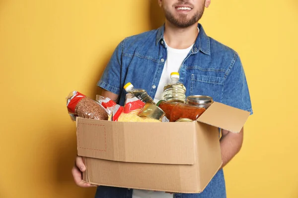 Junger Mann Hält Box Mit Spenden Auf Farbigem Hintergrund — Stockfoto
