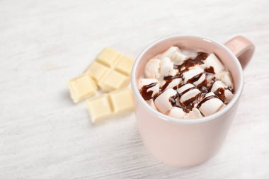 Fincan çikolatalı süt ile ışık ahşap arka plan üzerinde marshmallows