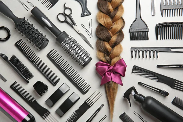 Flat lay composition with braid and hairdresser\'s tools on gray background