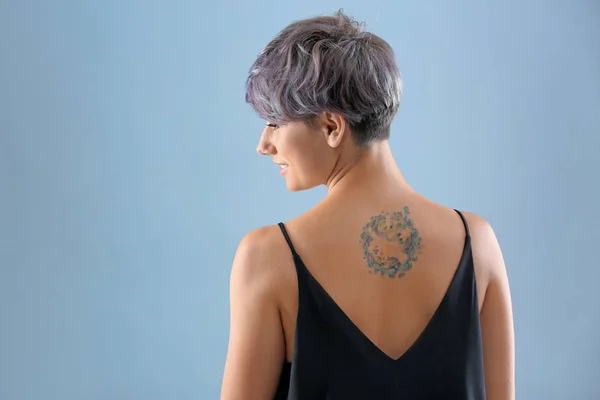 Young woman with tattoo on color background. Space for text