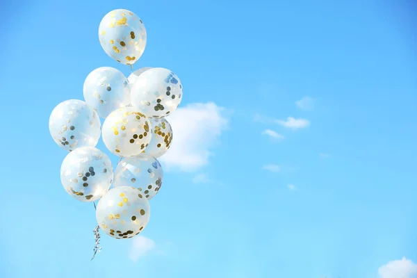 Glitter balloons against blue sky on sunny day outdoors. Space for text