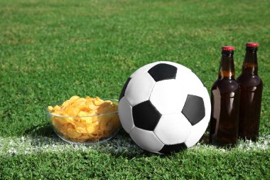 Futbol topuyla içecekler ve cips yeşil futbol alanı çimenlerin üzerinde