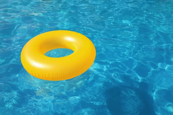 Inflatable ring floating in swimming pool on sunny day. Space for text