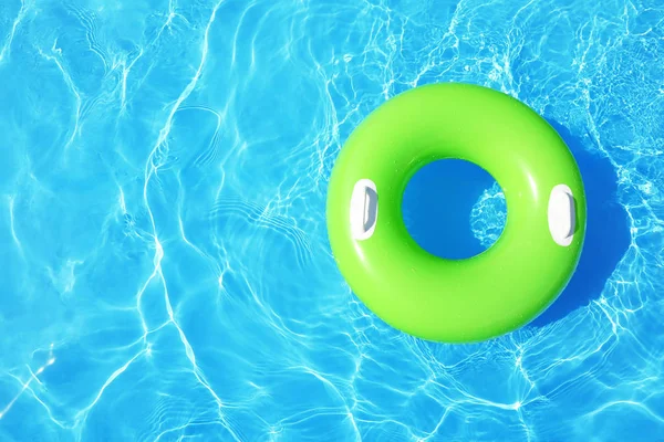 Inflatable ring floating in swimming pool on sunny day, top view with space for text