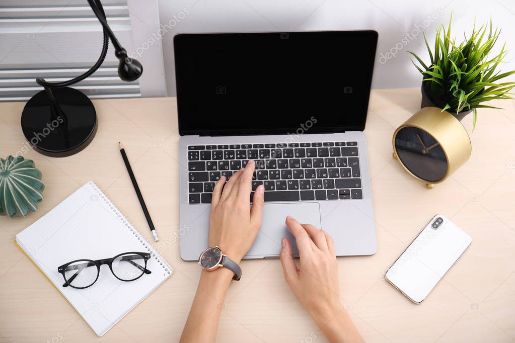 Female blogger using laptop at table, top view. Blank screen for mockup