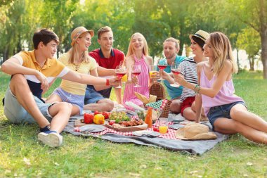 Mutlu arkadaşlar güneşli bir günde parkta piknik yapıyorlar.