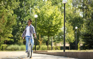 Yakışıklı genç hipster adam binicilik bisiklet park