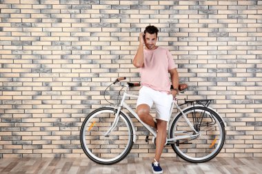 Yakışıklı genç hipster adam bisiklet yakınındaki tuğla duvar ile