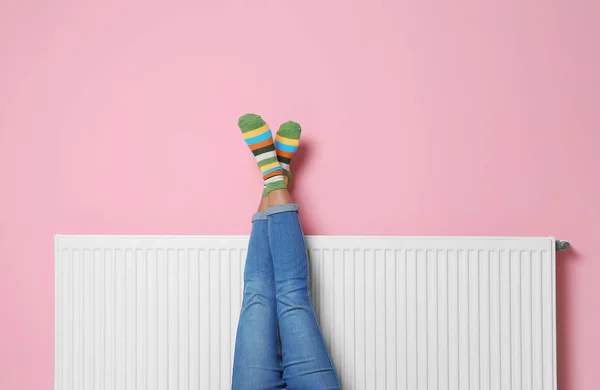 Frau Wärmt Beine Auf Heizkörper Nahe Farbwand — Stockfoto
