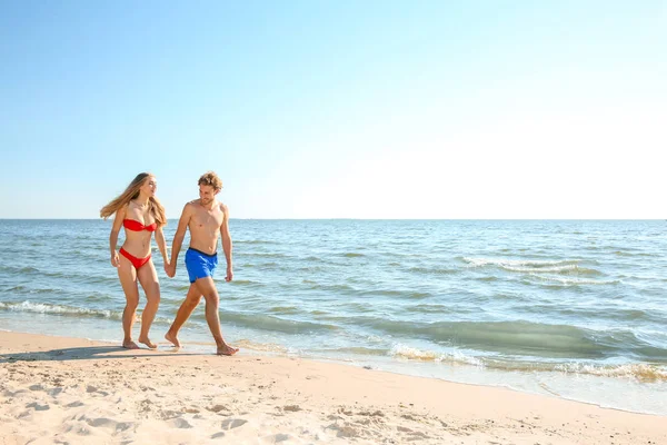 一緒に海岸を歩いてビーチウェアで幸せな若いカップル — ストック写真