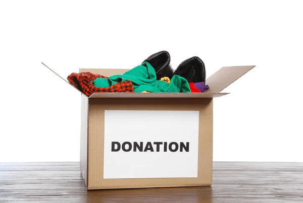 桌子上的衣服和鞋子的捐赠箱反对白色背景 — 图库照片