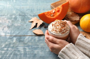 Cam fincan lezzetli kabak spice latte ahşap masa üzerinde closeup ile metin için yer tutan kadın