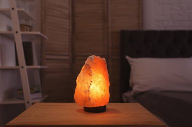Himalayan salt lamp on table in dark room clipart
