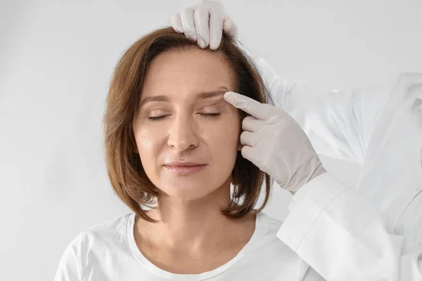 Médico Examinando Rosto Mulher Madura Antes Cirurgia Estética Fundo Branco — Fotografia de Stock