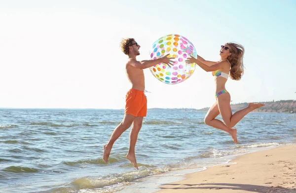 Feliz Pareja Joven Ropa Playa Saltando Con Bola Inflable Orilla — Foto de Stock