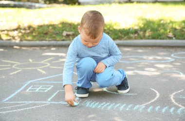 Küçük çocuk ile renkli tebeşir asfalt üzerinde çizim