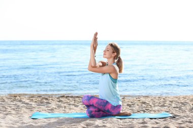 Genç kadının sabah sahilde Yoga egzersizleri yapması