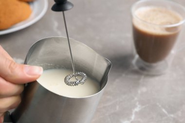 Masada sürahi içinde süt frother aygıt kullanan kadın