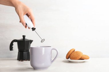 Tablo bardakta süt frother kullanan kadın. Metin için yer