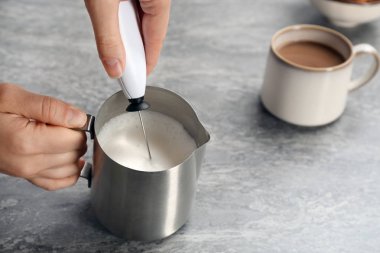 Sürahi kahve masada yakınındaki süt frother kullanan kadın